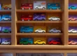 Prateleiras organizadas com coleções de Hot Wheels em blisters protegidos e miniaturas expostas em nichos de madeira.