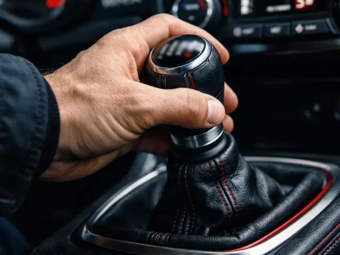 Close-up de mão de motorista trocando marcha, ilustrando hábitos que podem afetar a transmissão do veículo.