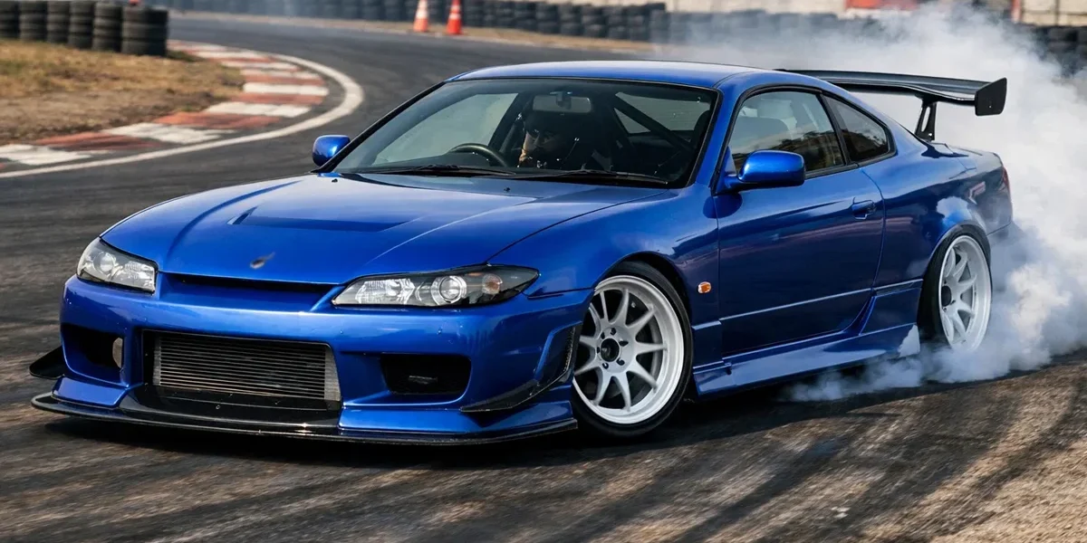 Nissan Silvia S15 azul Spec-R preparado para drift em uma pista, destacando o design icônico e as rodas esportivas.
