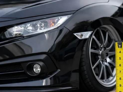 Carro rebaixado passando por medição de altura de 10 centímetros com fita métrica para legalização no DETRAN.