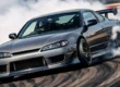 Um Nissan Silvia S15 realizando uma manobra de drift em pista, destacando a inclinação da carroceria e a fumaça nos pneus traseiros.