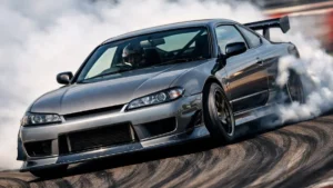Um Nissan Silvia S15 realizando uma manobra de drift em pista, destacando a inclinação da carroceria e a fumaça nos pneus traseiros.