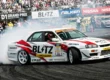 Ken Nomura pilotando o Nissan Skyline ER34 da Blitz em um ângulo extremo de drift durante o D1 Grand Prix.