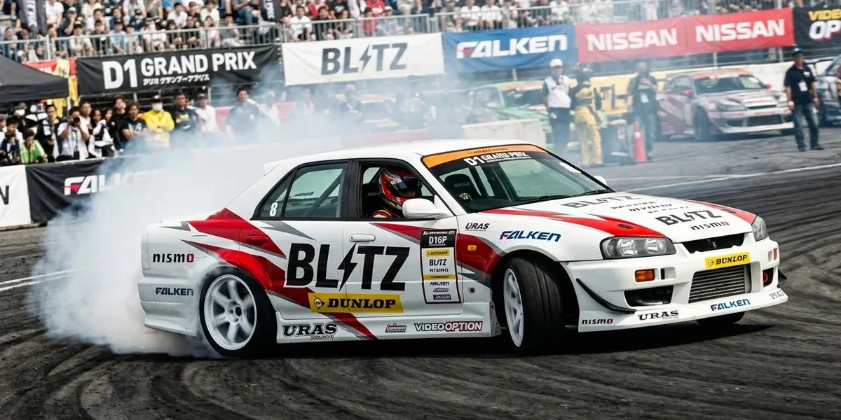 blitz-er34-nomuken-d1gp-drift Ken Nomura pilotando o Nissan Skyline ER34 da Blitz em um ângulo extremo de drift durante o D1 Grand Prix.