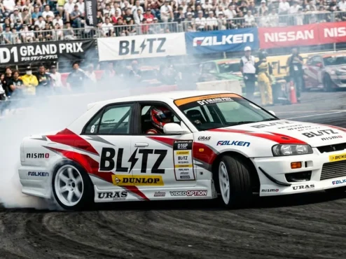 blitz-er34-nomuken-d1gp-drift Ken Nomura pilotando o Nissan Skyline ER34 da Blitz em um ângulo extremo de drift durante o D1 Grand Prix.