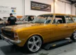 Carro clássico modificado em uma oficina com foco em rodas e suspensão, representando a cultura de customização e isenção de impostos.
