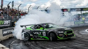 Carro de drift elétrico de alta performance em ângulo acentuado soltando fumaça densa dos pneus em uma pista de asfalto.