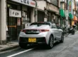 Um esportivo Honda S660 prata estacionado em uma rua de Tóquio, exibindo a característica placa amarela dos Kei Cars.