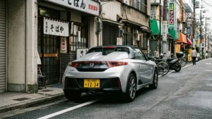 Um esportivo Honda S660 prata estacionado em uma rua de Tóquio, exibindo a característica placa amarela dos Kei Cars.