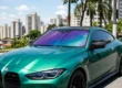 Carro esportivo com película camaleão no parabrisa apresentando variações de tons roxo e azul sob a luz solar.