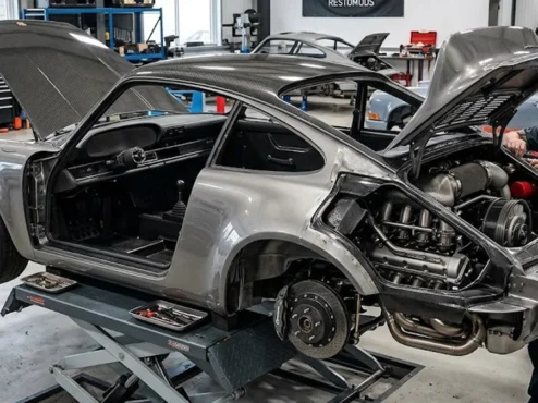projeto-restomod-porsche-911-singer-style-detalhes-mecanicos Um Porsche 911 clássico em processo de restomod, exibindo motor moderno e acabamento em fibra de carbono.
