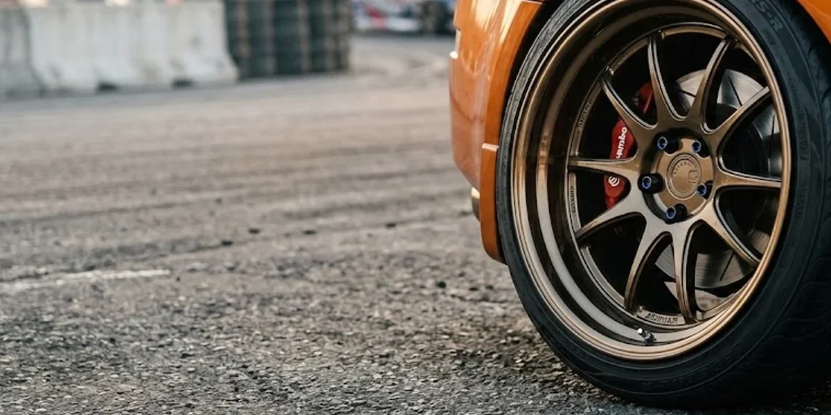 Close-up de uma roda esportiva com borda profunda apresentando estilo poke, saindo levemente da linha do para-lama do carro.