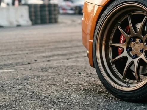 roda-esportiva-fitment-poke-paralama Close-up de uma roda esportiva com borda profunda apresentando estilo poke, saindo levemente da linha do para-lama do carro.