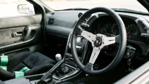 Detalhe de um volante esportivo de marca Nardi instalado em um cockpit de carro customizado, mostrando o acabamento em couro.