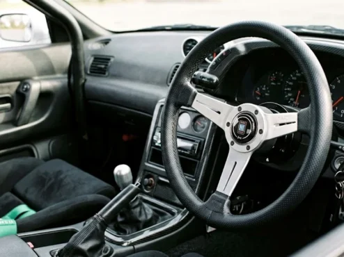Detalhe de um volante esportivo de marca Nardi instalado em um cockpit de carro customizado, mostrando o acabamento em couro.