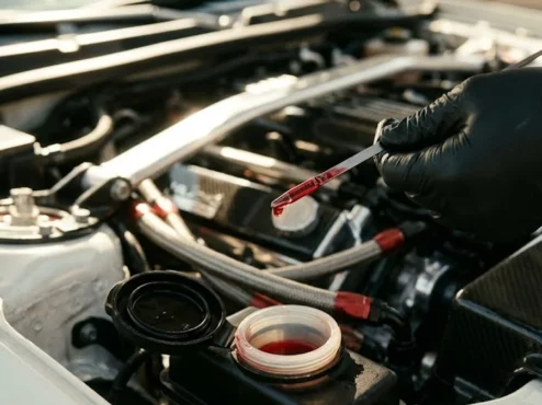 Mecânico inspecionando o fluido de direção hidráulica limpo em um reservatório de carro esportivo em uma oficina.