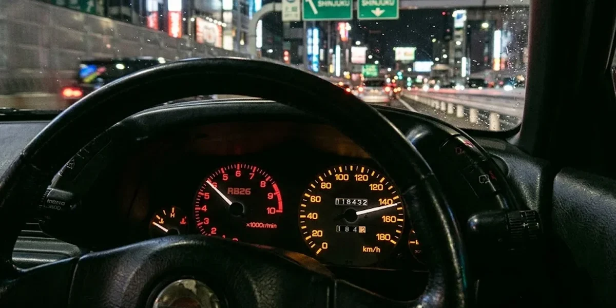 Close-up de um velocímetro de um Nissan Skyline R32 marcando o limite máximo de 180 km/h em um painel JDM.