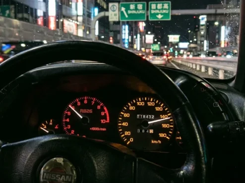 Close-up de um velocímetro de um Nissan Skyline R32 marcando o limite máximo de 180 km/h em um painel JDM.
