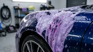 Detalhe de descontaminação química em carro esportivo com espuma reagindo a partículas ferrosas na pintura.