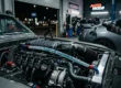 Close-up de um motor de alta performance e uma mão despejando aditivo de combustível premium em um tanque de carro à noite.