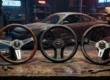 Três volantes esportivos originais Nardi, Momo e Vertex alinhados sobre uma bancada em uma oficina de preparação automotiva.