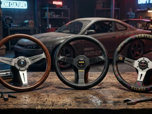 comparativo-volantes-jdm-nardi-momo-vertex Três volantes esportivos originais Nardi, Momo e Vertex alinhados sobre uma bancada em uma oficina de preparação automotiva.