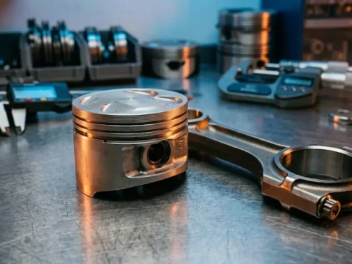 Vista detalhada de um pistão e biela forjados para alta performance em uma bancada de oficina mecânica profissional.