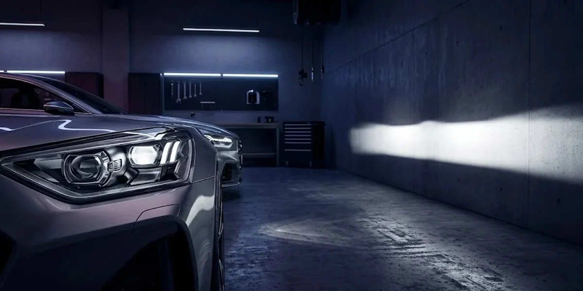 Farol esportivo automotivo com lente projetora exibindo uma linha de corte de luz perfeita contra uma parede escura.