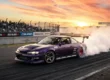 Carro japonês clássico Nissan Silvia modificado realizando manobra de drift em pista com muita fumaça nos pneus.