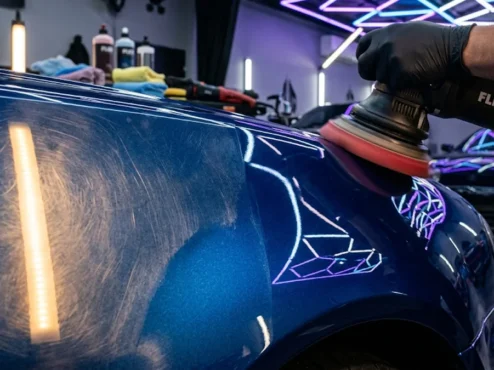 processo-polimento-tecnico-verniz-automotivo-detalhamento Polimento técnico profissional em para-lama de carro esportivo azul metálico com politriz orbital em estúdio de detalhamento.
