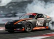Carro de competição Nissan Z de Chris Forsberg realizando manobra de drift em alta velocidade com esterço total das rodas.