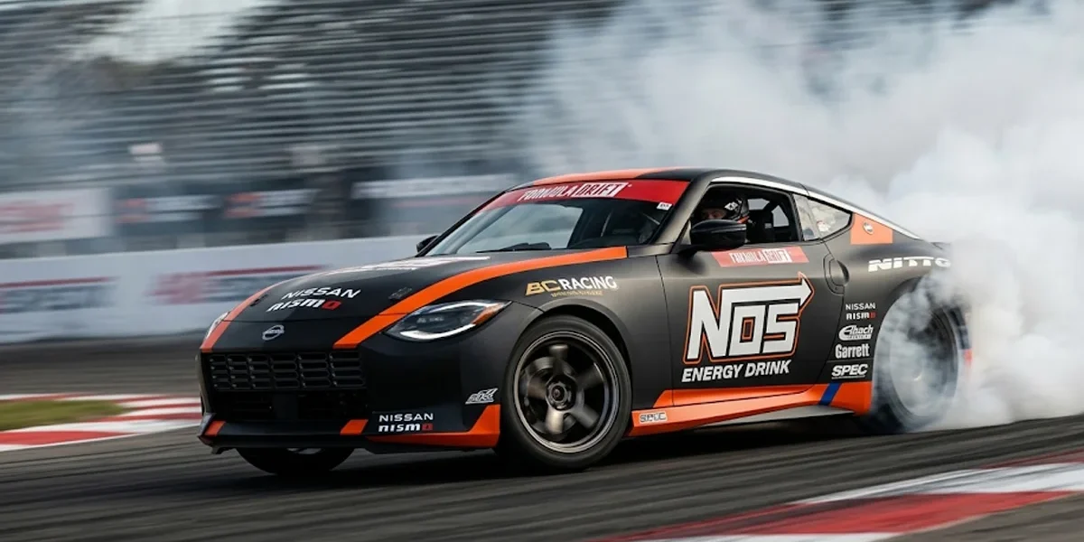 Carro de competição Nissan Z de Chris Forsberg realizando manobra de drift em alta velocidade com esterço total das rodas.