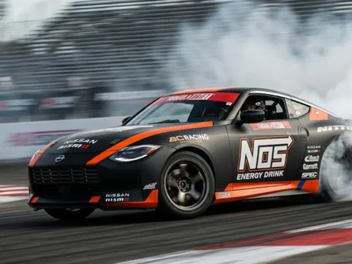 Carro de competição Nissan Z de Chris Forsberg realizando manobra de drift em alta velocidade com esterço total das rodas.