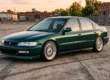 Honda Accord EXR verde dos anos 1990 rebaixado com rodas clássicas prata de três peças e estilo Clean em um pátio urbano.