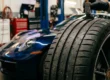 Ferramenta de profundímetro medindo os sulcos e o indicador TWI de um pneu de alta performance em uma oficina automotiva.