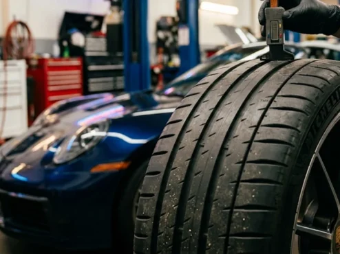 Ferramenta de profundímetro medindo os sulcos e o indicador TWI de um pneu de alta performance em uma oficina automotiva.
