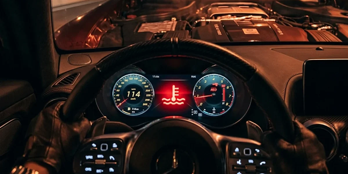 Foto detalhada do painel de instrumentos de um carro focado na luz vermelha de alerta de temperatura do motor acesa.
