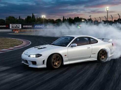 Nissan Silvia S15 branco fazendo drift em uma pista de corrida durante o entardecer, com fumaça saindo dos pneus traseiros.