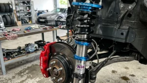 Conjunto de suspensão coilover ajustável com corpo rosqueado e molas esportivas instalado na caixa de roda de um carro de alta performance.