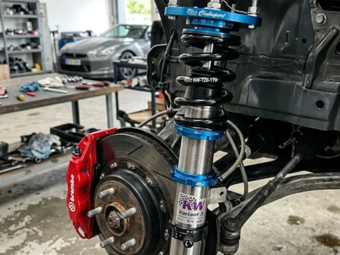 Conjunto de suspensão coilover ajustável com corpo rosqueado e molas esportivas instalado na caixa de roda de um carro de alta performance.
