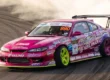 Nissan Silvia S15 rosa e roxo de Naoki Nakamura fazendo drift no D1GP com extrema fumaça e agressividade.