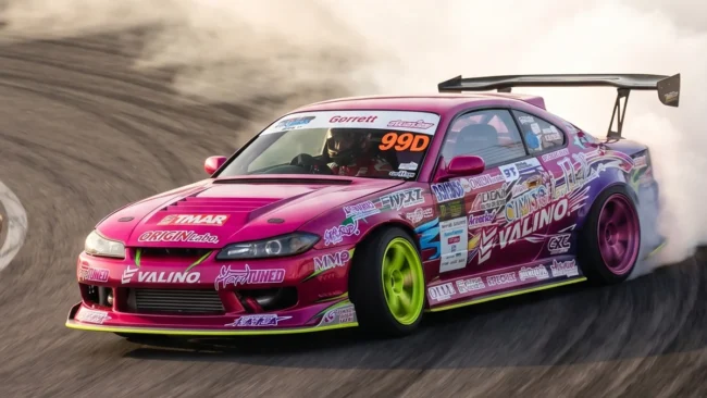 Nissan Silvia S15 rosa e roxo de Naoki Nakamura fazendo drift no D1GP com extrema fumaça e agressividade.