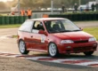 Fotografia em movimento de um Suzuki Swift GTi vermelho atacando a zebra em uma curva de autódromo.