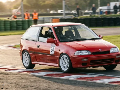 Fotografia em movimento de um Suzuki Swift GTi vermelho atacando a zebra em uma curva de autódromo.