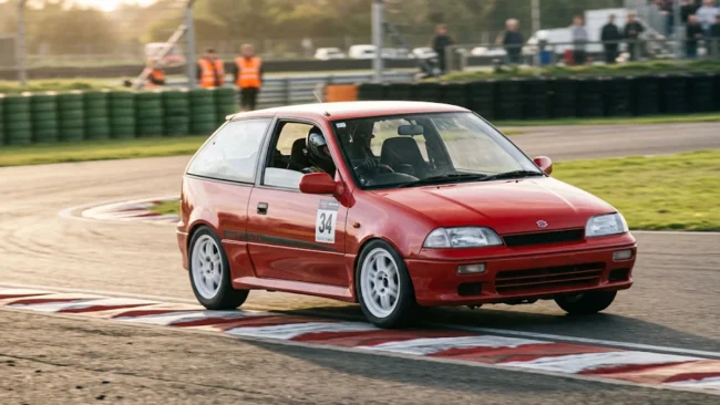 Fotografia em movimento de um Suzuki Swift GTi vermelho atacando a zebra em uma curva de autódromo.