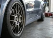 Roda esportiva montada rente ao para-lama de um carro, destacando o fitment agressivo proporcionado pelo uso de espaçadores.